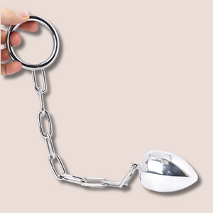 A full length image of the anal egg and steel cock ring with chain.