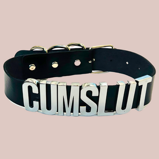 A close up view of the Cumslut collar, you can see the silver shiny lettering that is all in capital letters. There is matching silver buckles at the back.