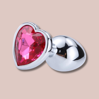 A close up view of the heart shaped rose pink. jewelled end to the large butt plug from House Of Chastity.