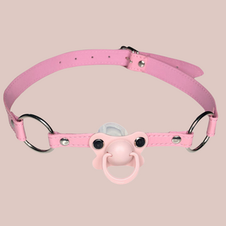 A pink pvc long gag that has a pale pink dummy fixed to the front which the wearer will have to hold in their mouth and a  silver buckle fastening to the back.