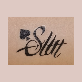 An image of the Slut temporary tattoo from House Of Chastity shown when applied to the skin.