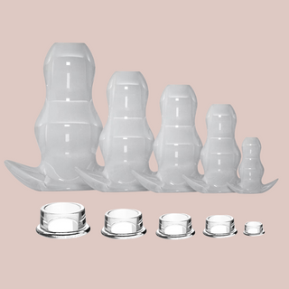 All 5 sizes of the Hollow Anal Plug available from right to left, X-Small, Small, Medium, Large, X-Large. The matching closing plugs are shown below each anal plug.